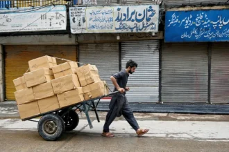 یک کارگر پاکستانی در حال کشیدن چرخ دستی