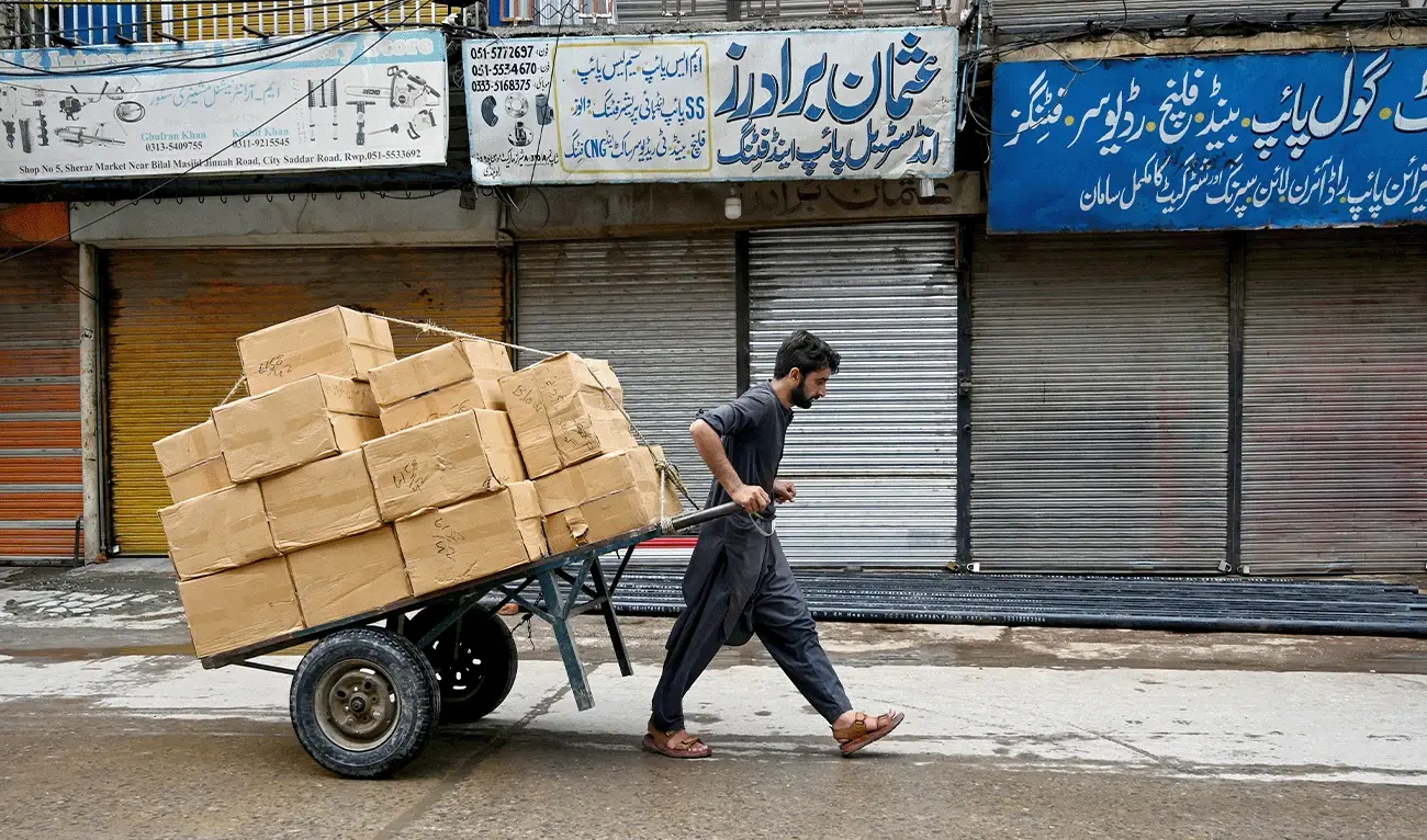 یک کارگر پاکستانی در حال کشیدن چرخ دستی